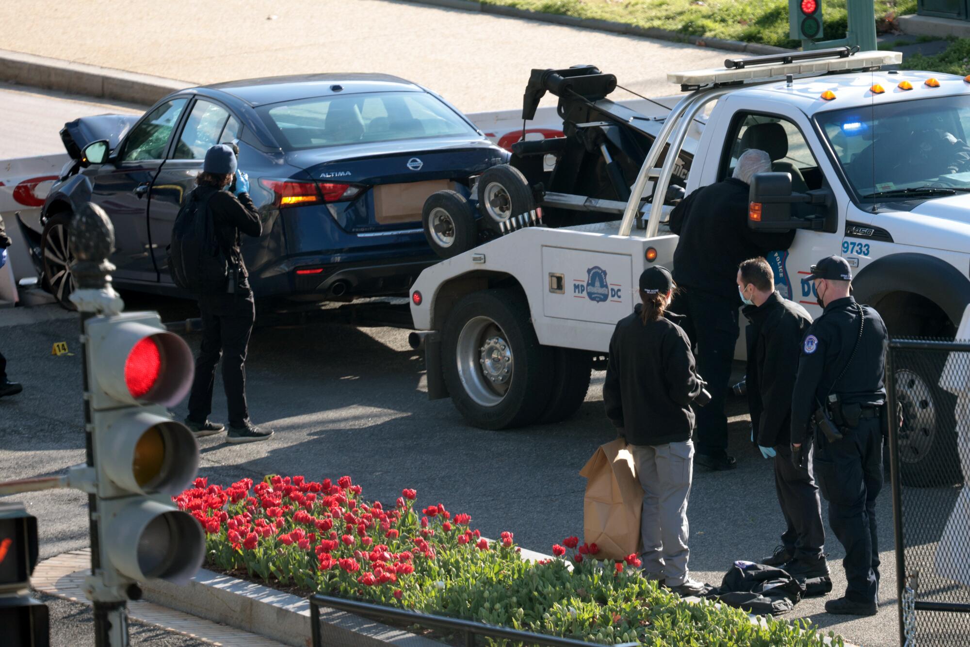 A tow truck removes a car as law enforcement collect evidence at the scene after a vehicle charged a barricade 