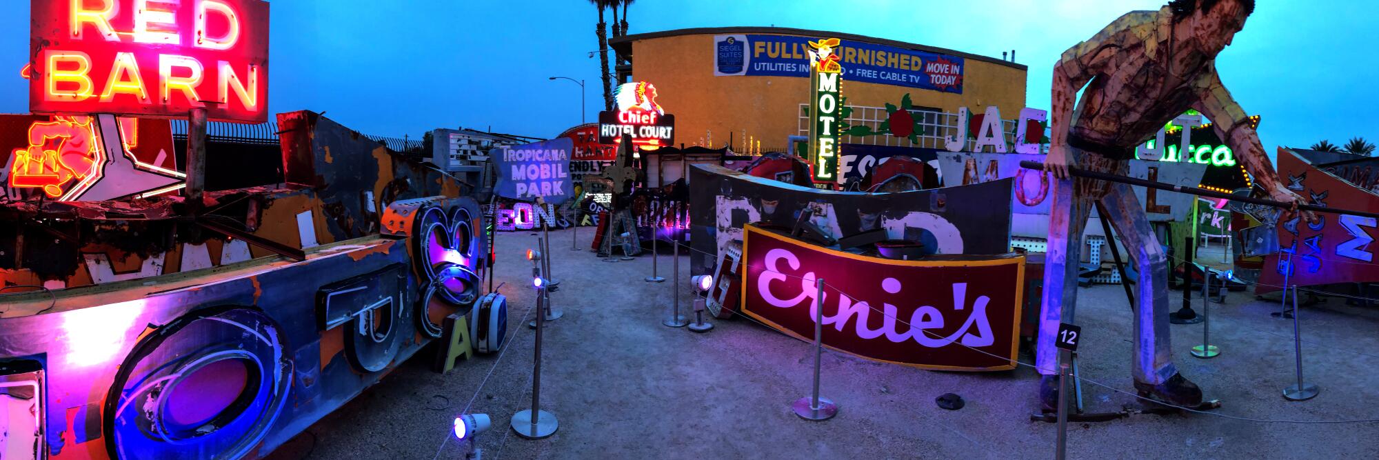 Neon Museum, Las Vegas, with neon signs for Red Barn and Motel, buildings and a tall statue of a man.