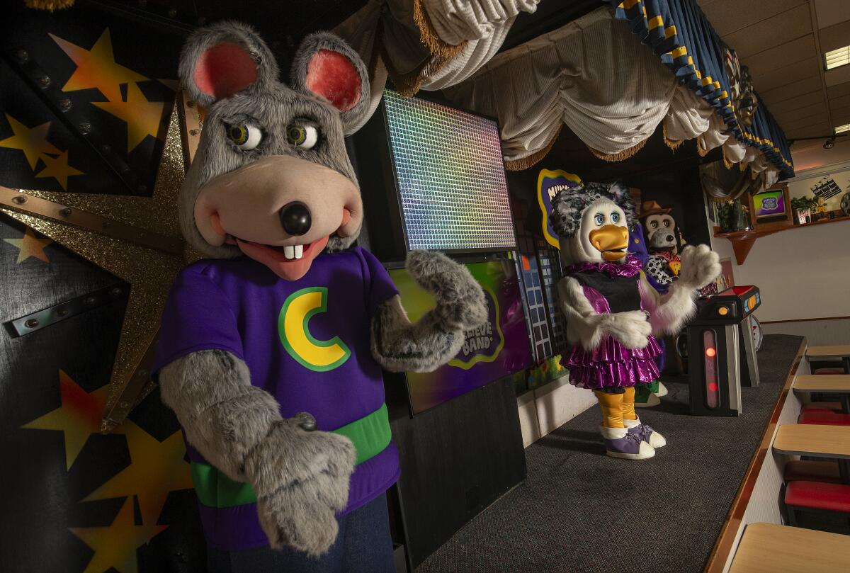 A robotic Chuck E. waves his giant robotic mouse hands to the crowd.