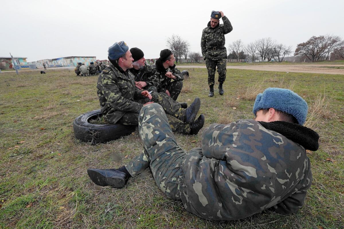 Ukrainian soldiers in southern Crimea sit in front of the Belbek airstrip being held by Russian troops.