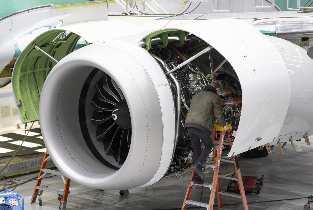 A Boeing employee works on the engine of a 737 MAX on the final assembly line at Boeing's Renton plant, June 15, 2022 in Renton, Wash. Delta is ordering 100 of Boeing's 737 Max 10 airplanes, with an option to purchase 30 more, as the airline looks to keep up with surging travel demand. Delta Air Lines said Monday, July 18, 2022 that the airplanes, which can seat up to 230 people, will reduce fuel use and emissions by 20-30% compared to those it replaces. (Ellen M. Banner/The Seattle Times via AP, Pool)