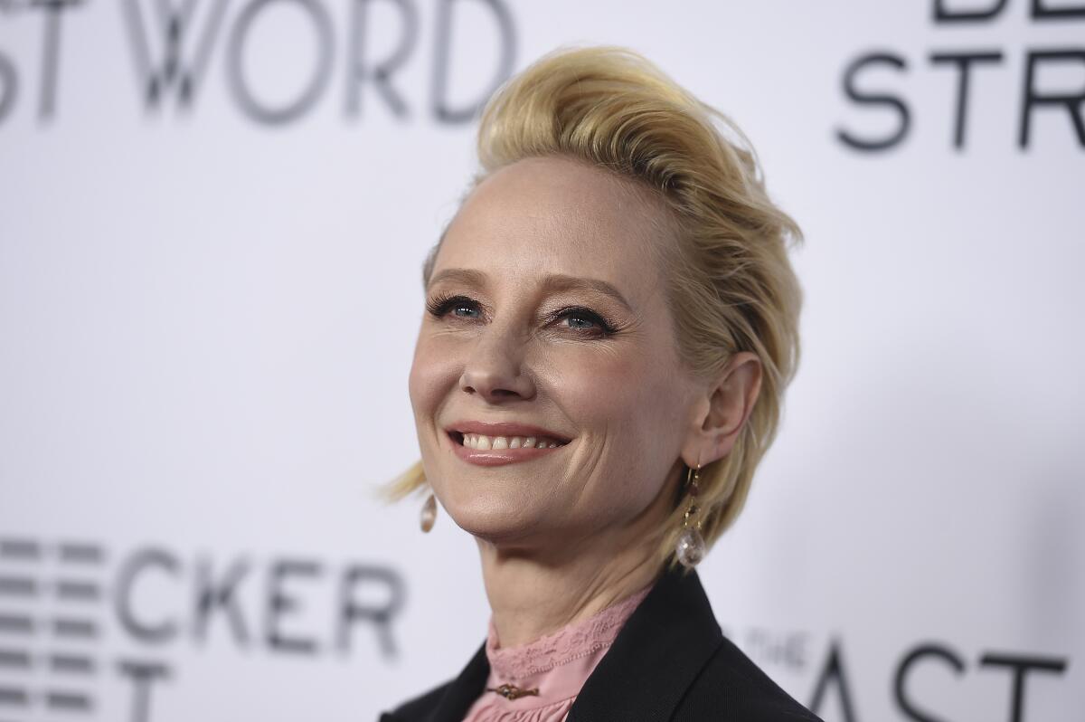 A woman with short, blond hair smiling and wearing dangly earrings