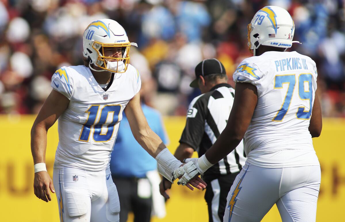 Chargers quarterback Justin Herbert and offensive tackle Trey Pipkins slap hands.