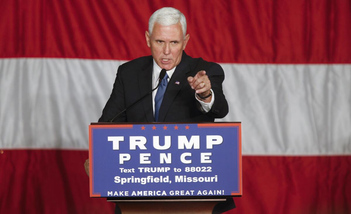 Former Vice President Mike Pence, at a campaign-stop podium, points at the crowd. 