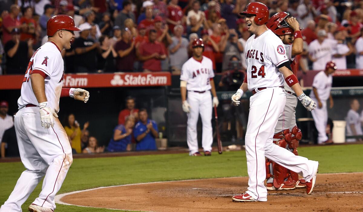 Los Angeles Angels' C.J. Cron, right, and Mike Trout, left, smile after Cron hit a two-run home run, as Cincinnati Reds catcher Raffy Lopez stands at the plate during the first inning Tuesday.