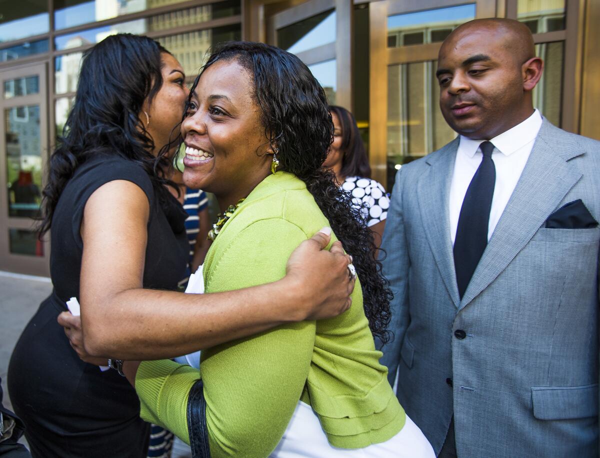 Shanesha Taylor is congratulated as Rev. Jarrett Maupin looks on outside Maricopa County Superior Court in Phoenix. Prosecutors and Taylor reached a deal to allow her to avoid prosecution for leaving her two young sons alone in a hot car while she was at a job interview.