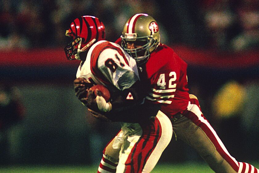 San Francisco 49ers Hall of Fame safety Ronnie Lott (42) stops Cincinnati Bengals wide receiver Cris Collinsworth.