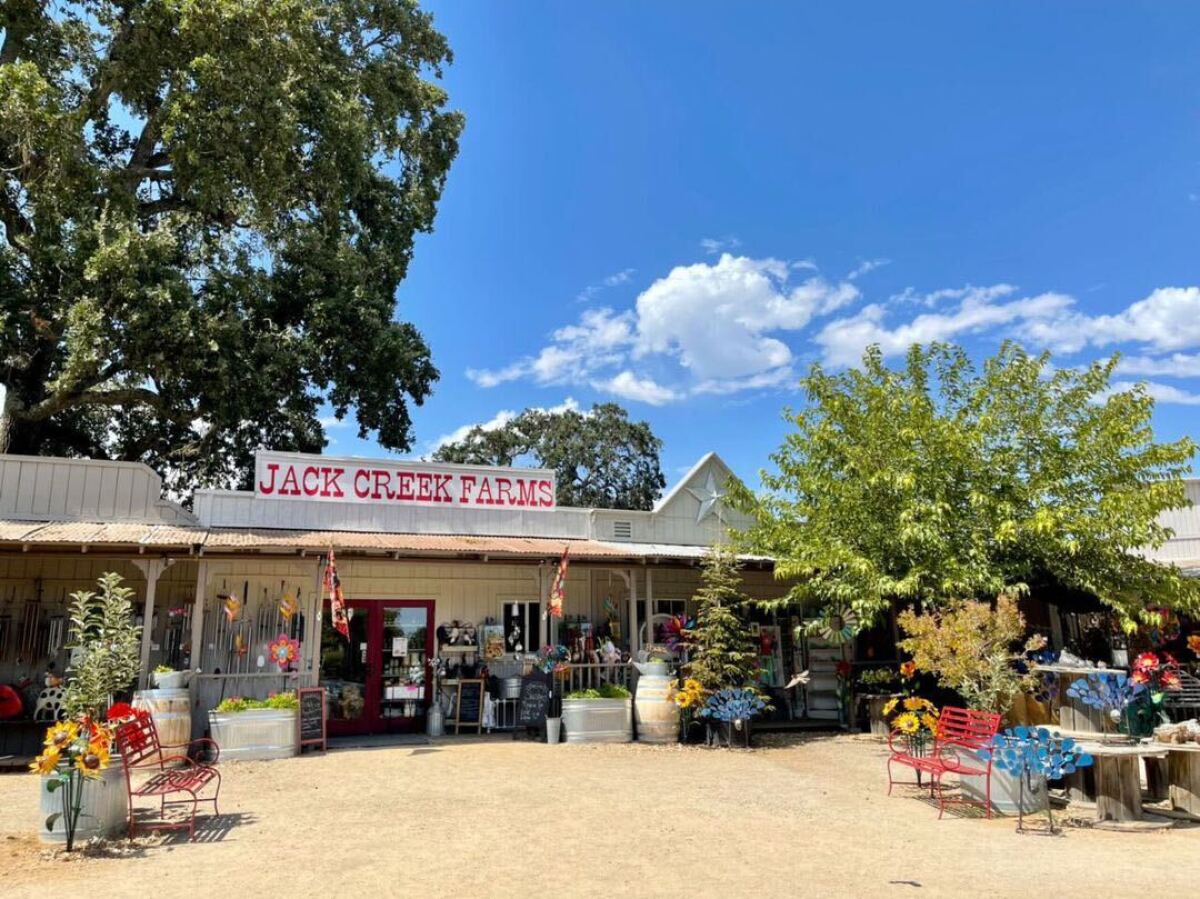 Exterior of a colorful country story, with a sign that says "Jack Creek Farms" in red over the front door. 