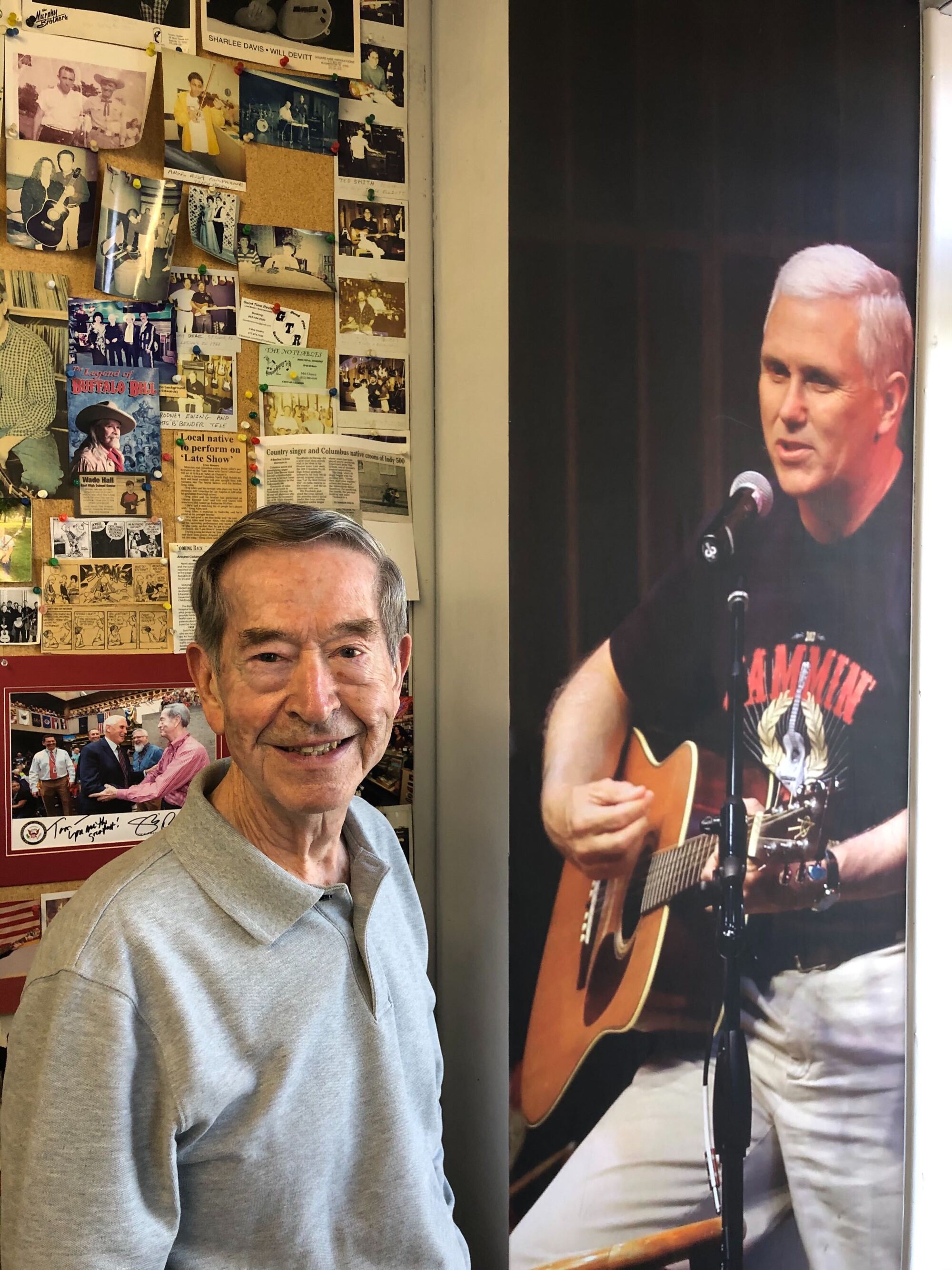 Tom Pickett at his Columbus, Ind., music shop next to a larger-than-life photo of Mike Pence playing guitar.