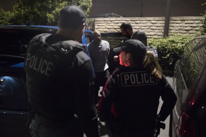 ICE agents surround a man at night.