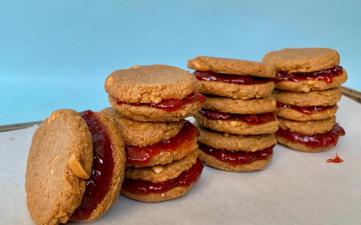 Three stacks of peanut butter and jelly cookies and one cookie on end, leaning on a stack.