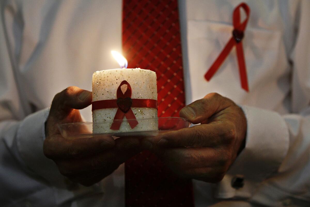 A candle with a red ribbon for HIV/AIDS awareness is carried during an event held by the Roman Catholic Archdiocese of Los Angeles in 2011.
