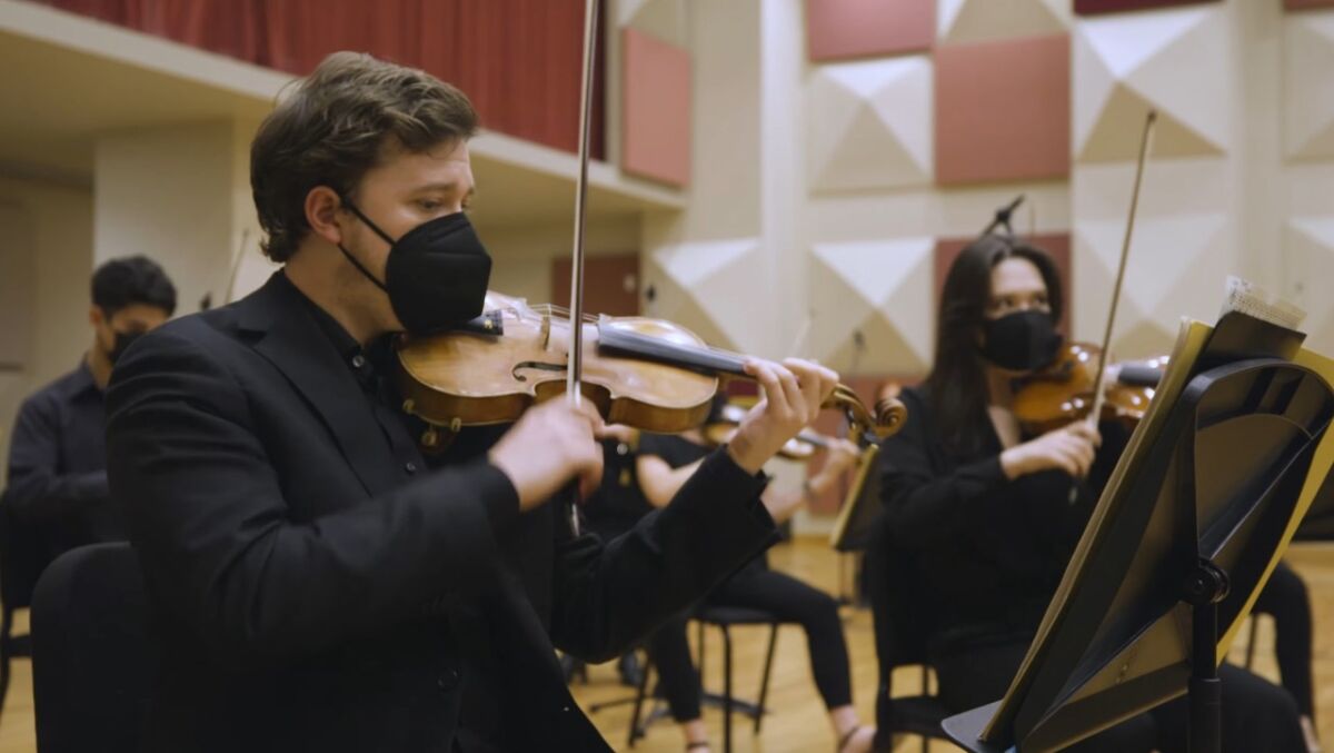 Two musicians perform while looking at sheet music.