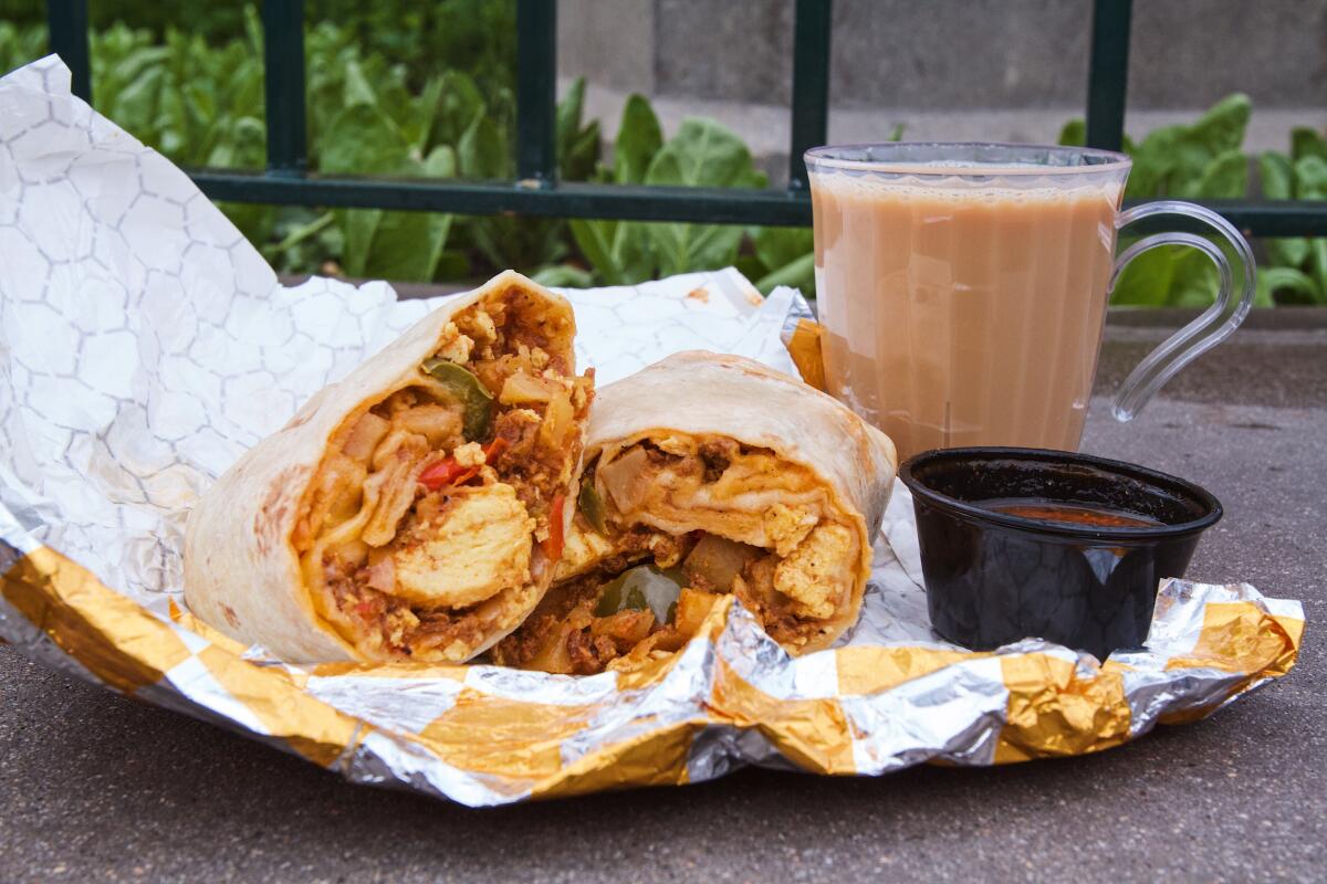 A halved chorizo breakfast burrito sits next to a cup of boozy hazelnut cream coffee.