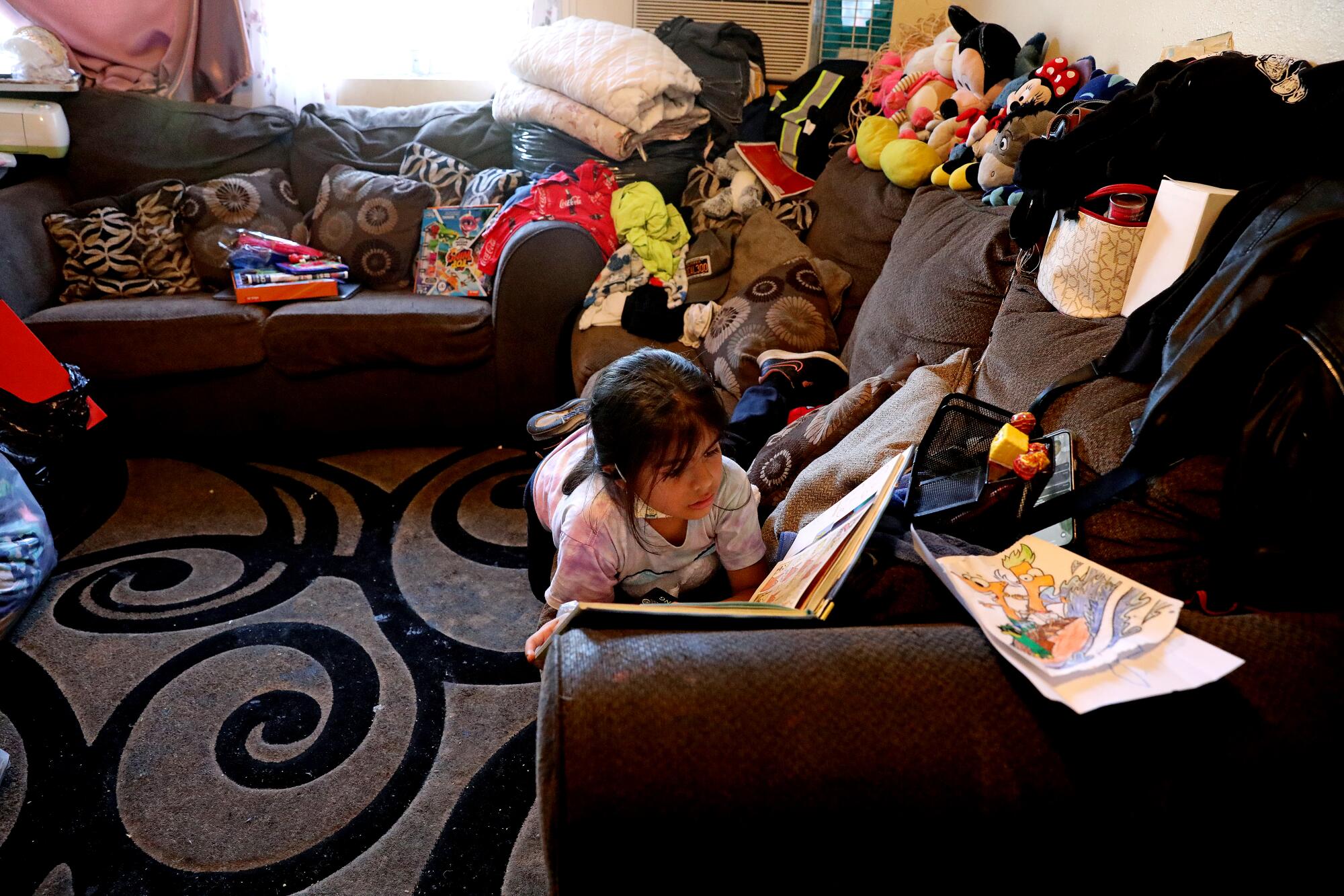Yaretzi Galicia, de 7 años, lee en la sala de estar del departamento de una habitación de la familia en Pico-Union.