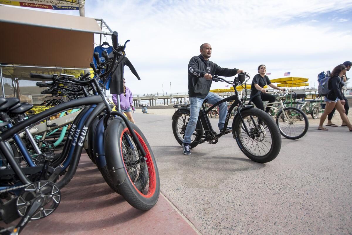 Joseph Ali, the owner of Zack's in Huntington Beach, puts away a rental e-bike on Wednesday.