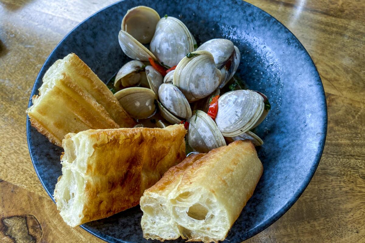 Clams in a buttery black pepper sauce with scallions, Thai basil and Fresno chiles with a Chinese doughnut