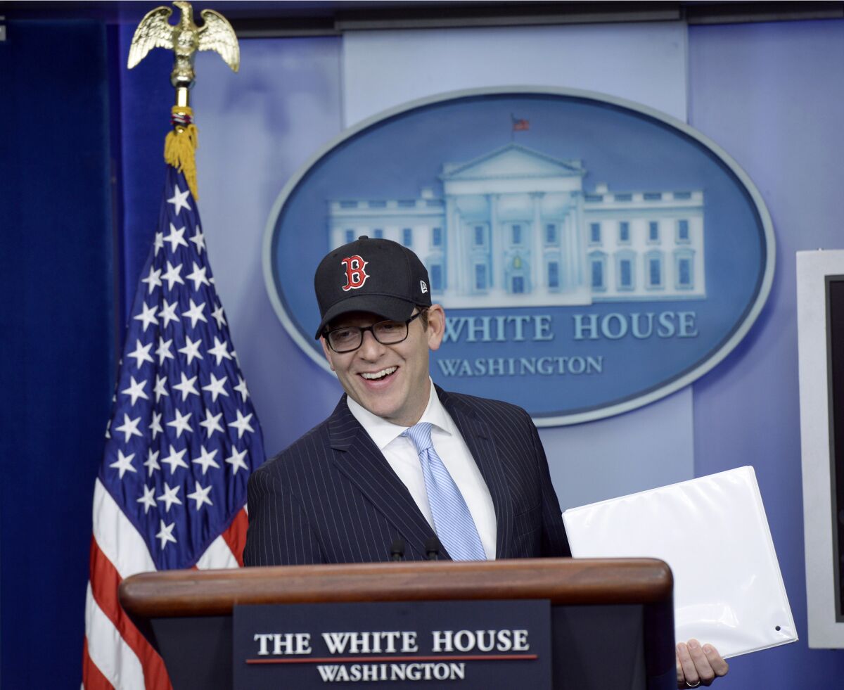 White House Press Secretary Jay Carney, wearing a Boston Red Sox baseball cap because the World Series champions were honored by the president, begins the daily briefing, where he announced that more than 7 million people have signed up for Obamacare.
