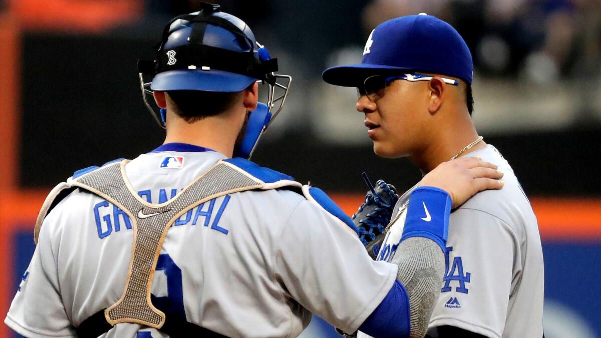 Dodgers catcher Yasmani Grandal talks to starter Julio Urias during his debut Friday in New York.