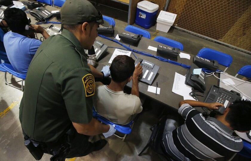 A U.S. Customs and Border Protection officer helps unaccompanied minors make phone calls after their detention last summer at the Mexican border. The influx of minors, as well as mothers with children, has contributed to a massive caseload in federal immigration courts, which Congress has failed to properly fund.