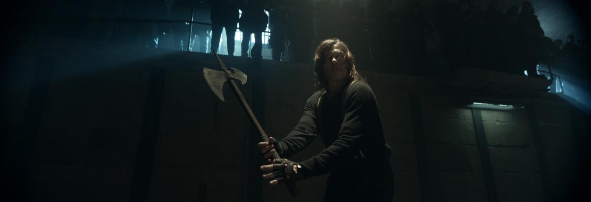 A man (Daryl, played by Norman Reedus) wields an axe in a makeshift arena - in the original, very wide aspect ratio.