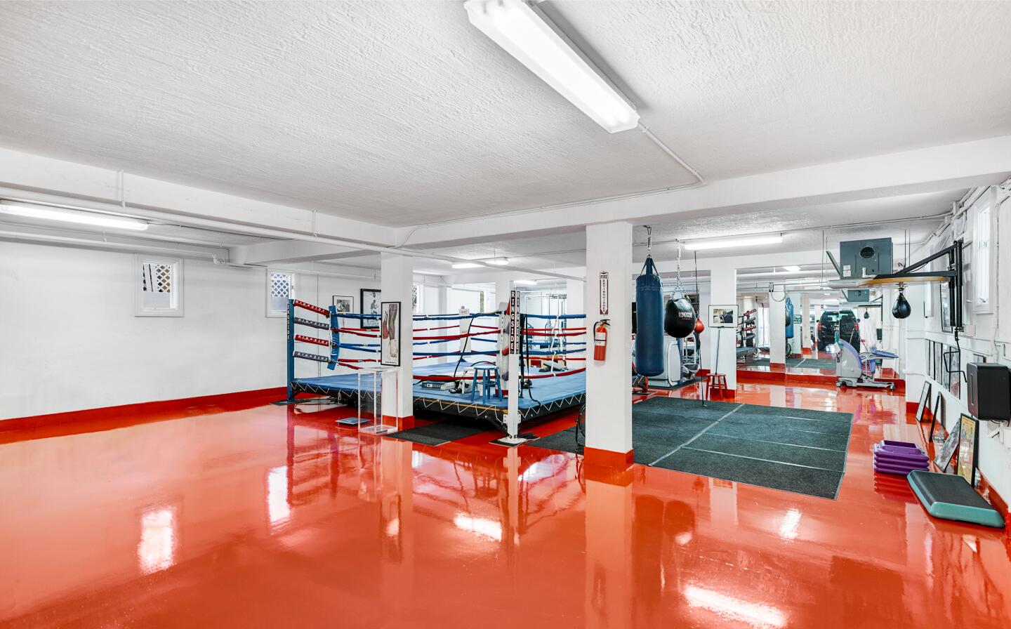 The boxing ring is near exercise equipment.