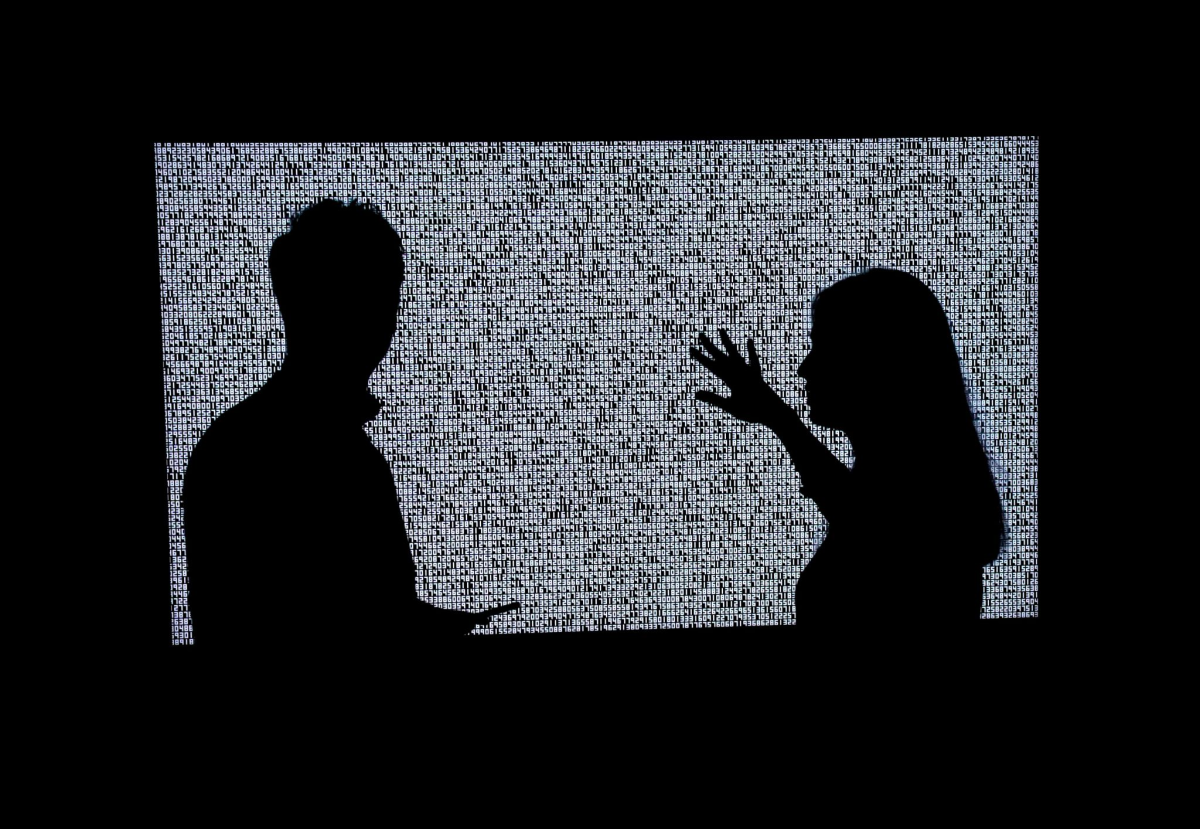 Silhouettes of two people in front of a work of art. 