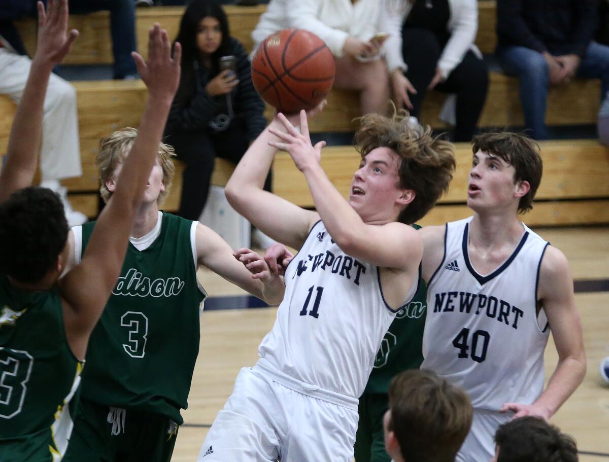Newport Harbor’s Levi Darrow (11) pulls up for a short jumper as Luke Bashore (40) trails behind during a Surf League game against Edison on Wednesday.