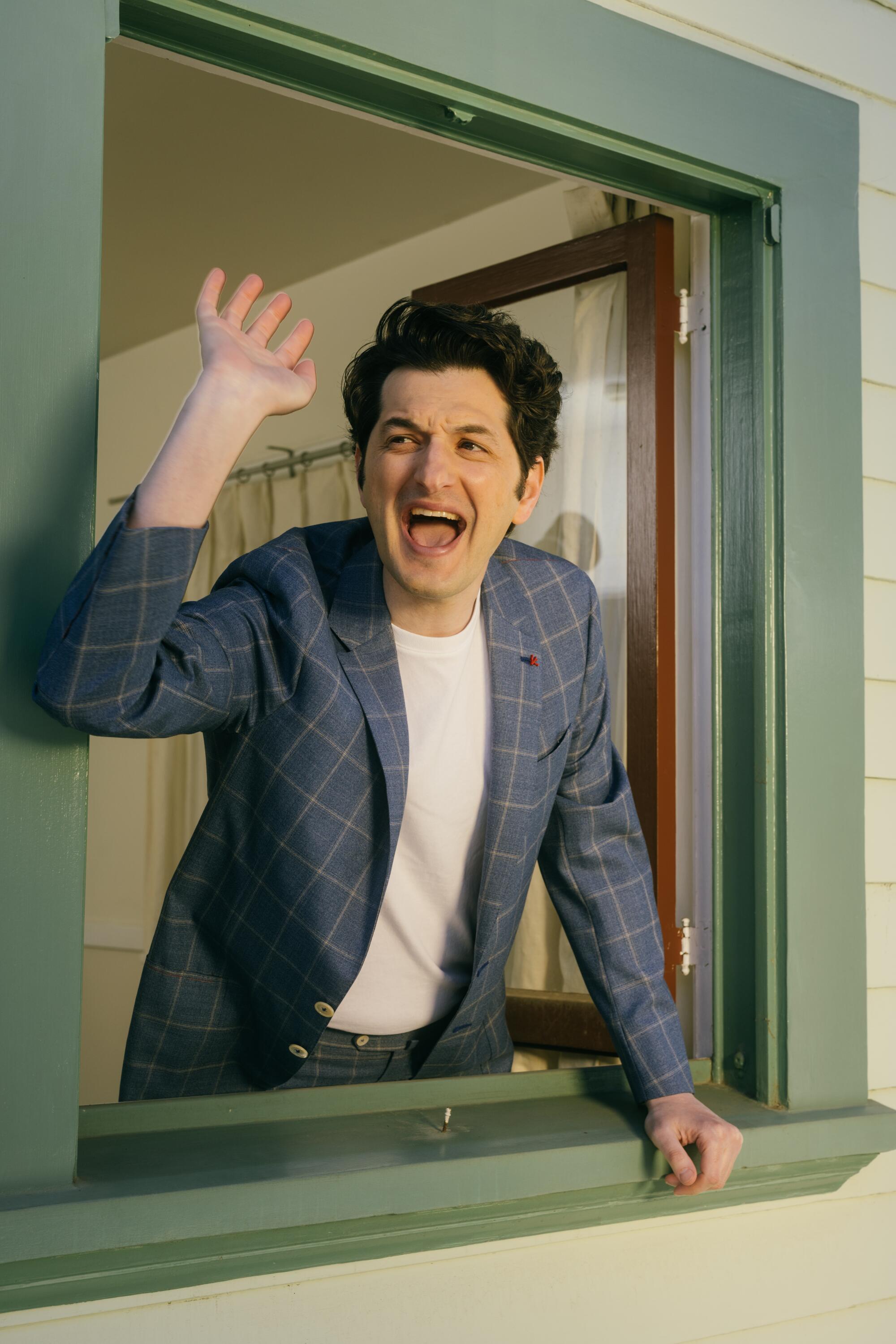 Ben Schwartz poses for a photo by yelling out of a window.