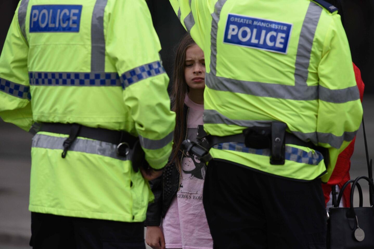 A woman and a young girl, who is wearing a T-shirt of singer Ariana Grande, talk to police May 23, 2017, near Manchester Arena in Manchester, England the day after an explosion at a concert by Grande killed 22 people.