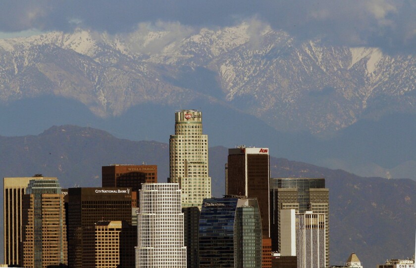 Snow-covered San Gabriel Mountains rise behind the downtown Los Angeles downtown skyline.
