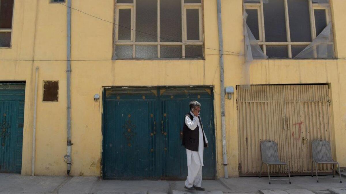 An Afghan man talks on a phone in front an international guest house that was attacked by gunmen in Kabul.