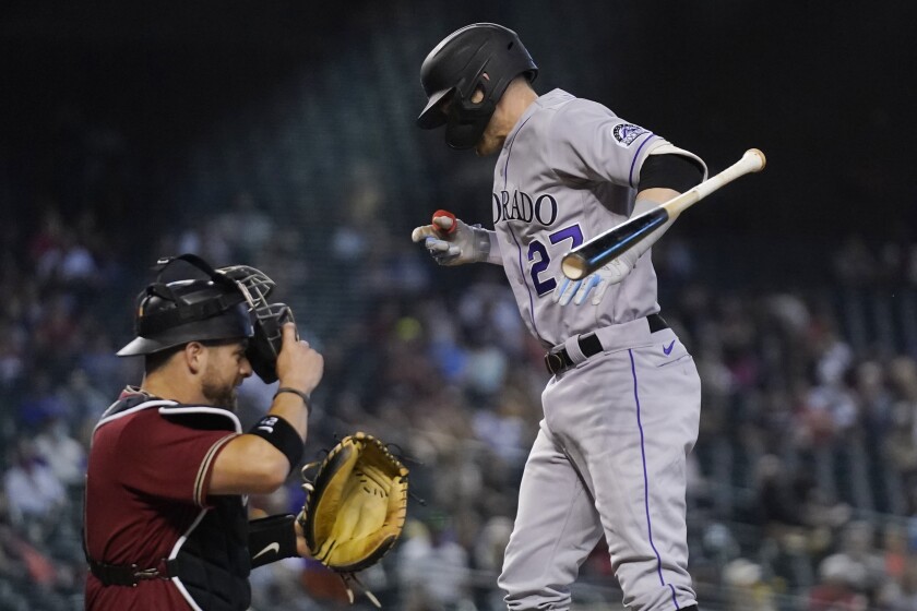 Colorado Rockies' Trevor Story, right, jumps in reaction to being hit by a pitch as Arizona Diamondbacks catcher Stephen Vogt, left, looks on during the eighth inning of a baseball game Sunday, May 2, 2021, in Phoenix. (AP Photo/Ross D. Franklin)