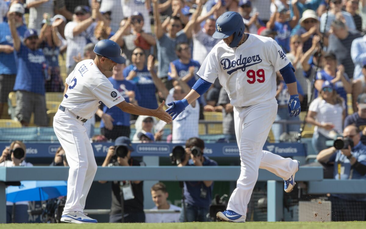 Dodgers pitcher Hyun-Jin Ryu is congratulated by third base coach Dino Ebel after hitting a solo home run.