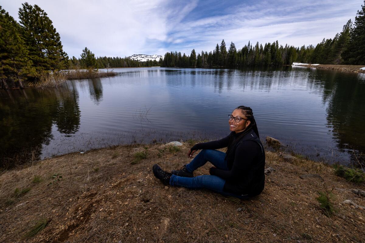A woman sits for a portrait beside a lake