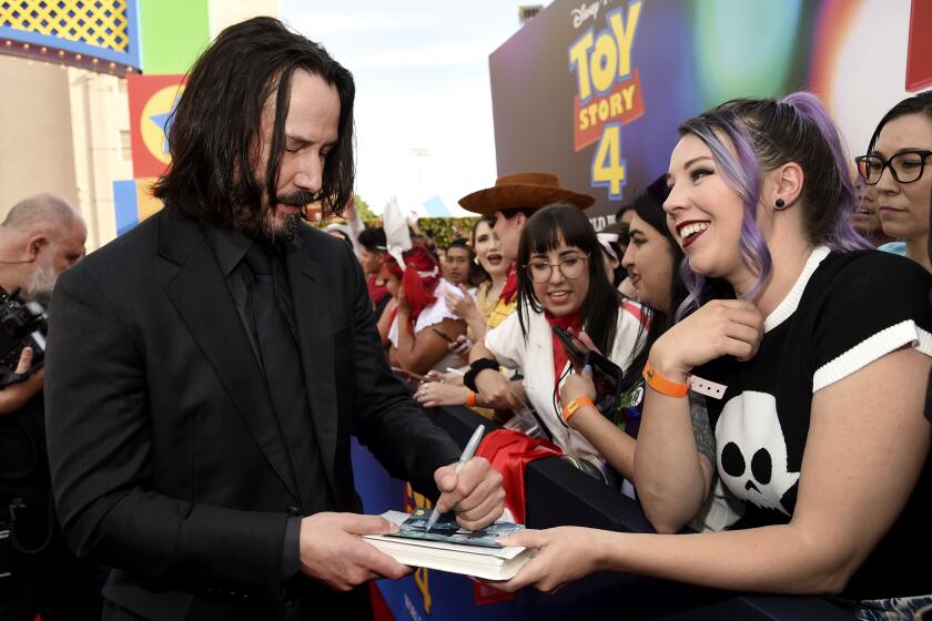 Keanu Reeves signs an autograph as he arrives at the world premiere of "Toy Story 4" on Tuesday, June 11, 2019, at the El Capitan in Los Angeles. (Photo by Chris Pizzello/Invision/AP)