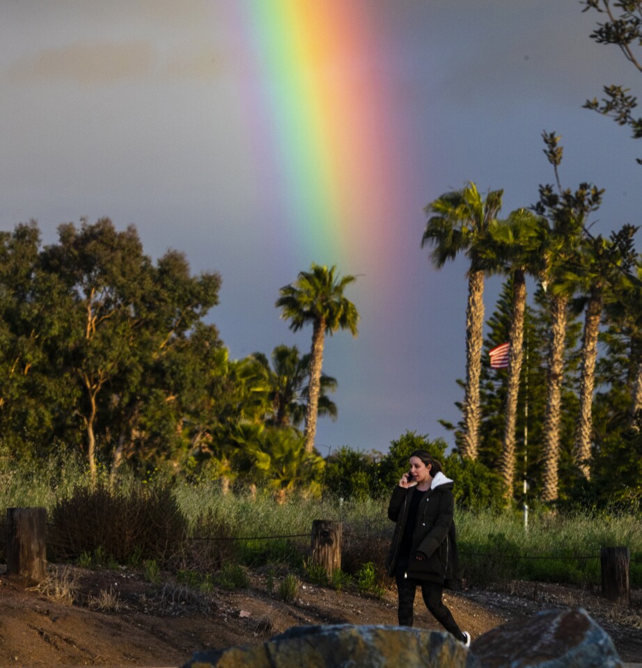 COSTA MESA, CA -- FRIDAY, APRIL 10, 2020: A rainbow appears behind a woman walking through Fairview Park in Costa Mesa on Good Friday April 10, 2020. Heavy rain is expected in Southern California on Friday as a low pressure system brings more moisture. About 1-2 inches of rain is expected in Los Angeles and Orange counties with temperatures reaching a high of 68 degrees. (Allen J. Schaben / Los Angeles Times)