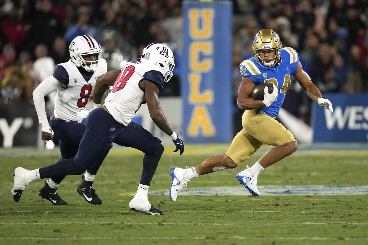 UCLA running back Zach Charbonnet dashes away form Arizona linebackers Sterling Lane II and Jerry Roberts.