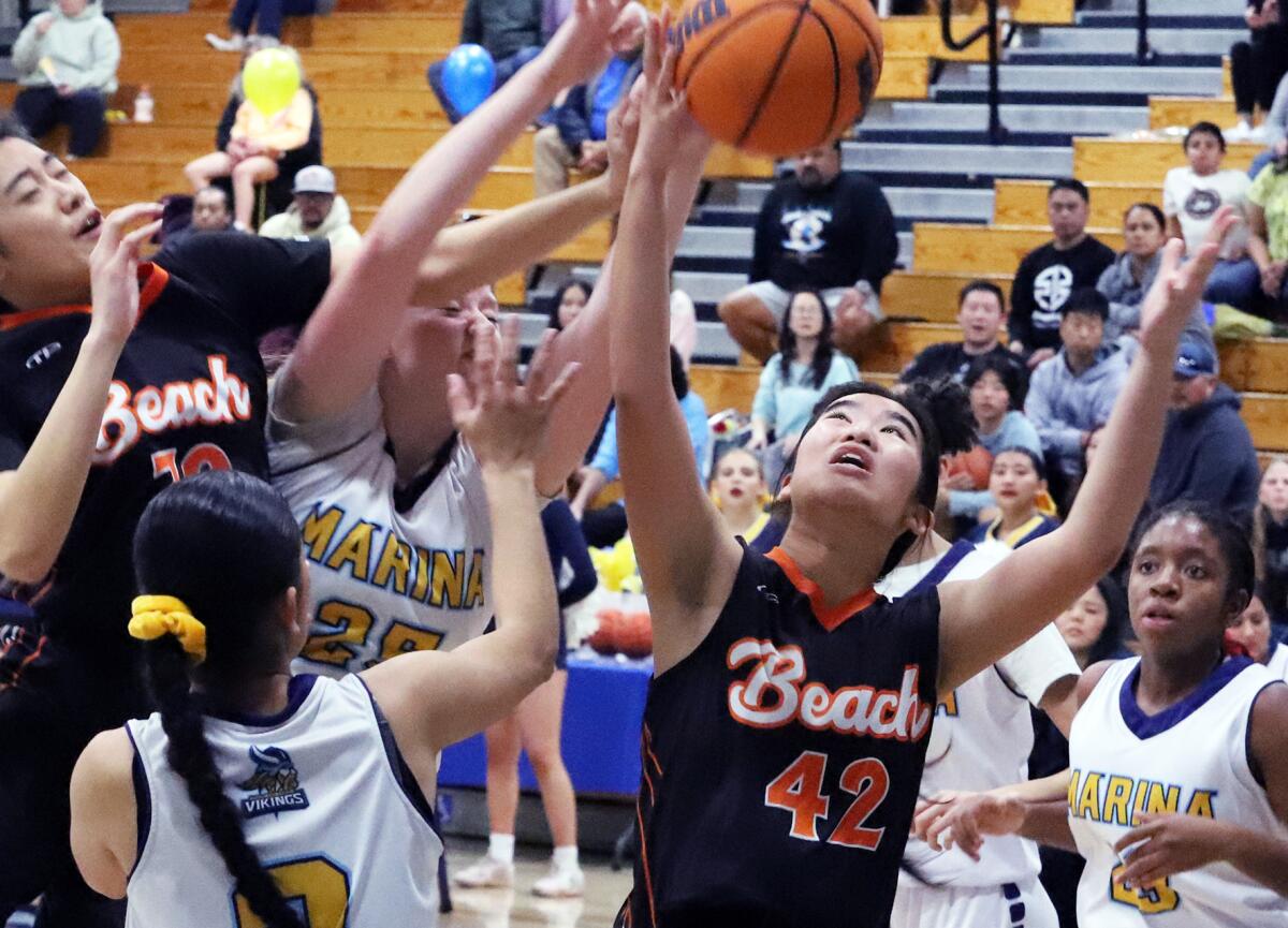 Huntington Beach's Emily Hoang (42) reaches for the rebound against Marina in a Wave League game on Monday.