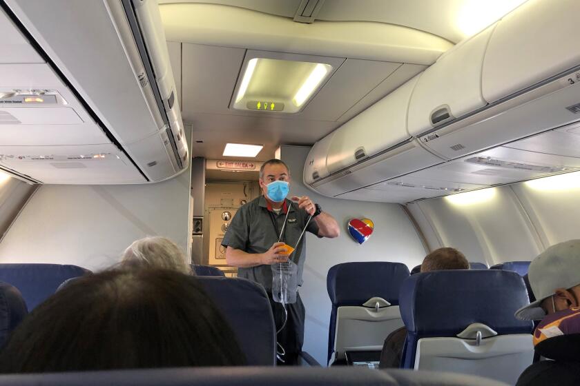 Flight attendant, wearing one mask, demonstrates the use of another at the outset of a Burbank-Las Vegas flight in early June.
