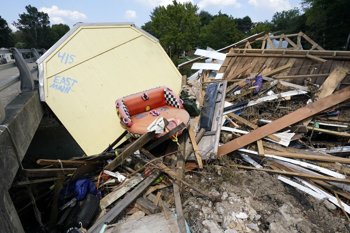 The address of a utility building is painted on the back as it sits lodged against a bridge with other debris, Aug. 25, 2021, in Waverly, Tenn. Ten families are suing CSX Transportation for up to $450 million over flooding that killed 20 people in Tennessee last year, claiming a clog underneath the railroad giant's bridge in rural Waverly allowed a “deadly tidal wave” to form. The lawsuit filed Tuesday, April 5, 2022 in circuit court in Humphreys County claims the bottlenecked culvert and the earthen railbed supporting CSX's elevated tracks formed a man-made dam, impeding the normal flow of Trace Creek. (AP Photo/Mark Humphrey, file)