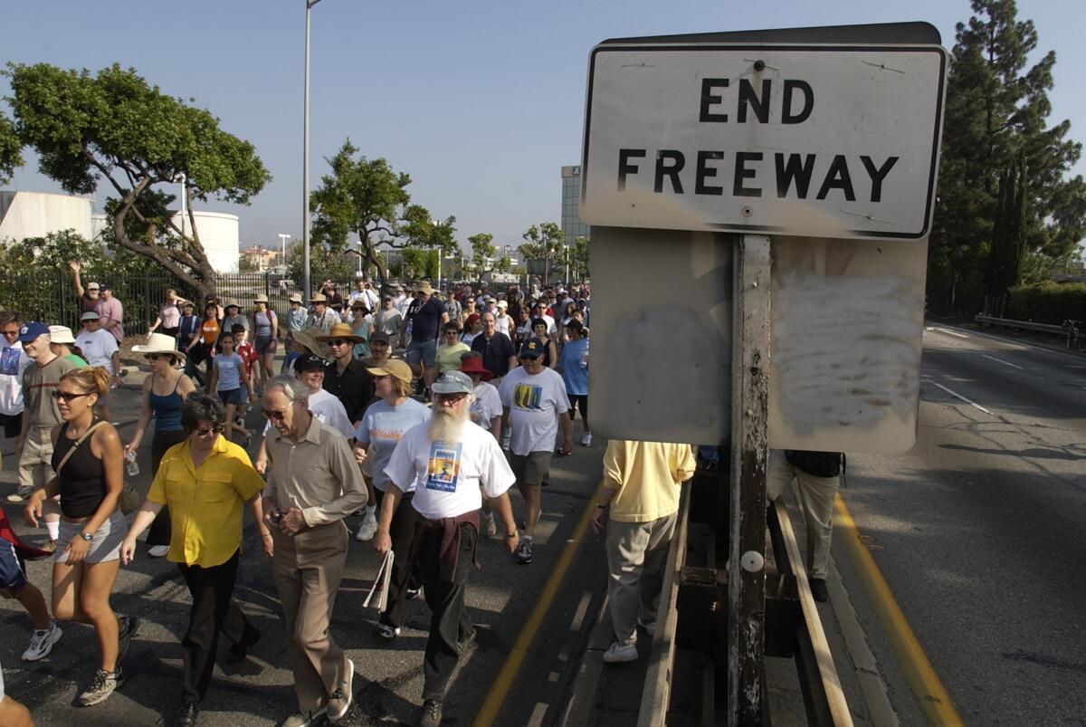 People walk on a freeway next to a road sign that says "End freeway"