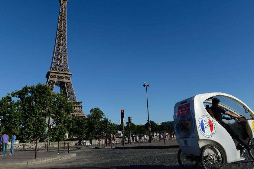 PARIS, FRANCE - JULY 31: Tourists ride in a bicycle taxi past the Eiffel Tower on July 31, 2013 in Paris, France. Several companies offer this new useful, fast and eco-friendly means of transport. (Photo by Pascal Le Segretain/Getty Images) ORG XMIT: 175350077
