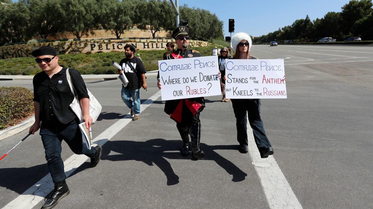 Mike Stutz and Laurel Trotter dress in Russian costumes as they march along Newport Coast Drive on Monday to protest Vice President Mike Pence as he attended a fundraiser at The Resort at Pelican Hill.