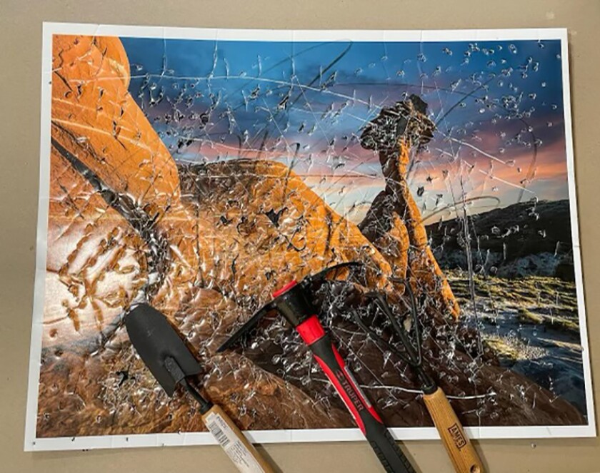 A damaged photo of a landscape by John Raymond Mireles and three garden tools