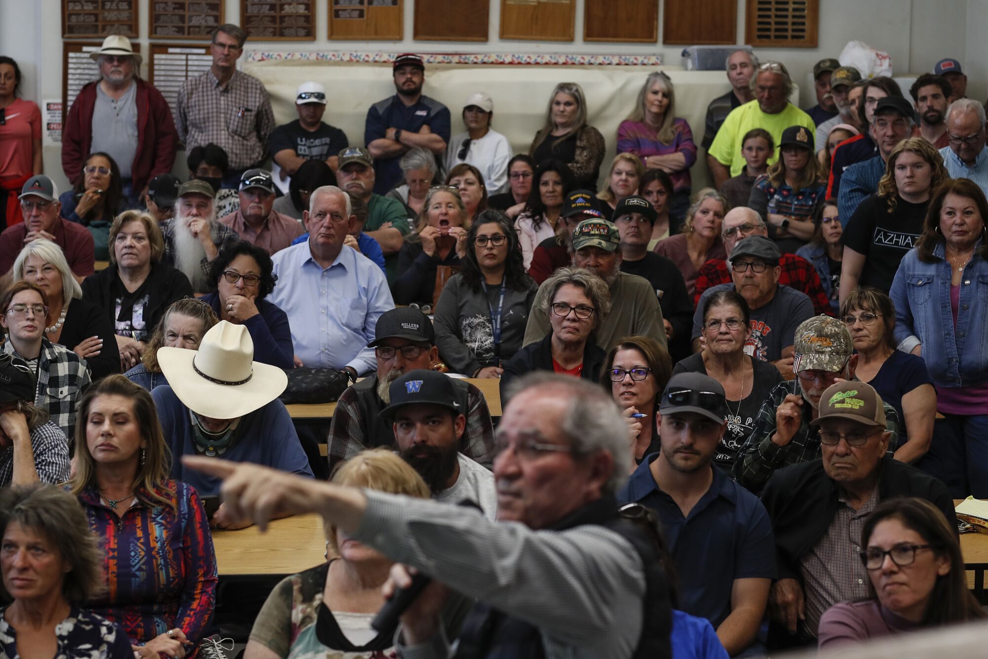 A seated audience watches a man speak into a microphone and point