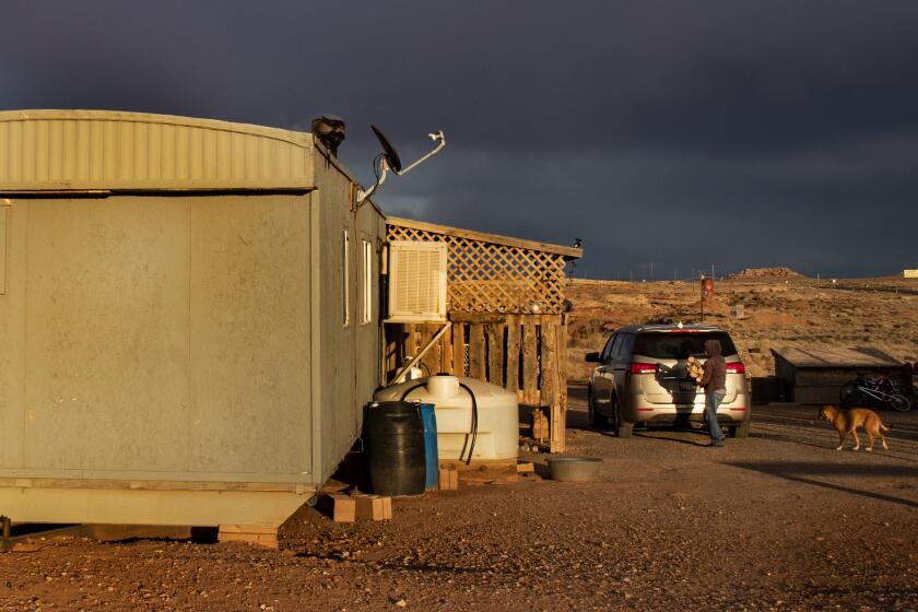 CAMERON, AZ - MARCH 27, 2020: A Navajo woman carries wood to heat her rural mobile home during freezing temperatures during the coronavirus pandemic on the reservation on March 27, 2020 in Cameron, Arizona. She doesn't have running water, which is becoming worrisome during the coronavirus pandemic. Now, more than 75 Navajos have tested positive. She said she's tried to get supplies at the local Sam's Club, but many of the shelves are bare. She did not want to give her name.(Gina Ferazzi/Los AngelesTimes)