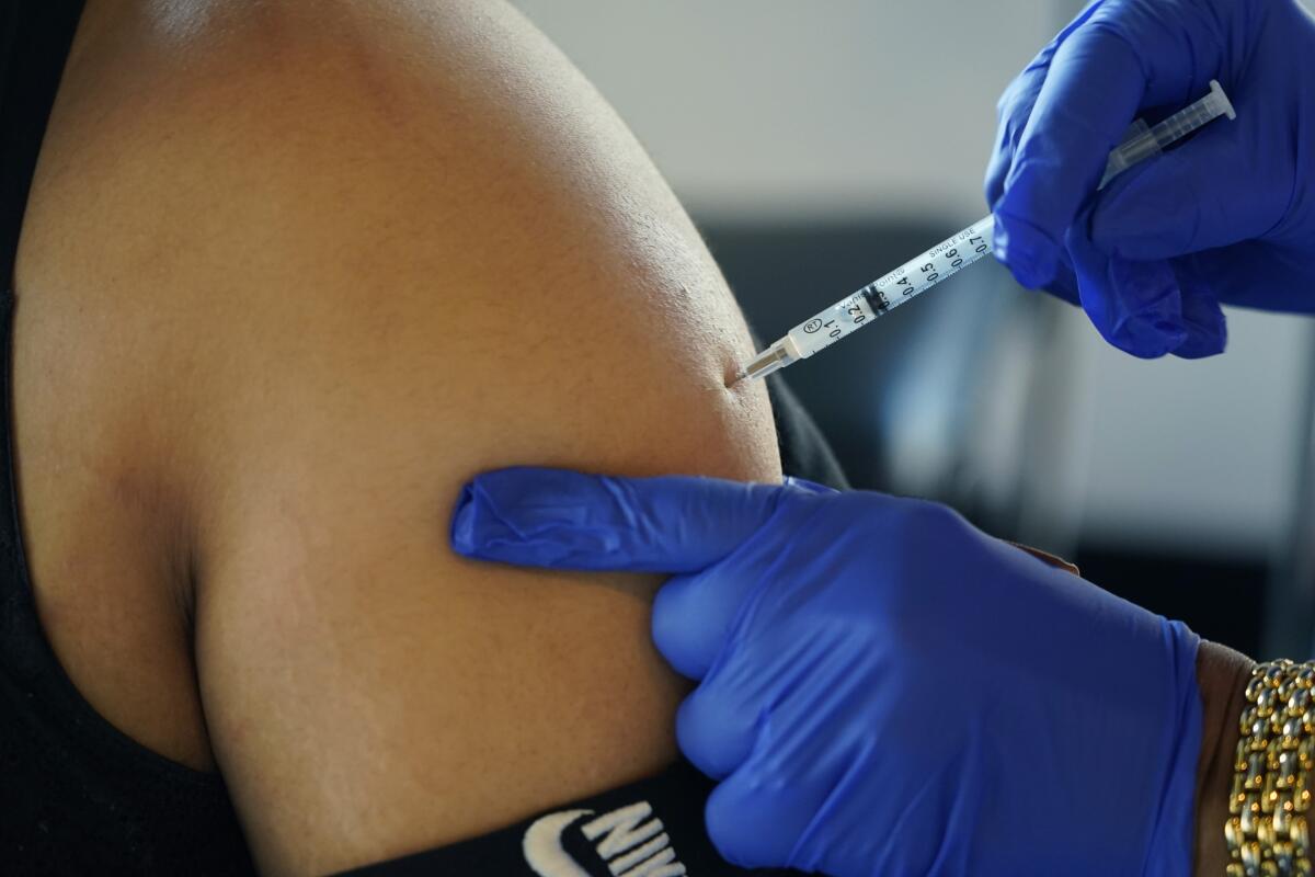 A nurse administers a shot in a person's arm.