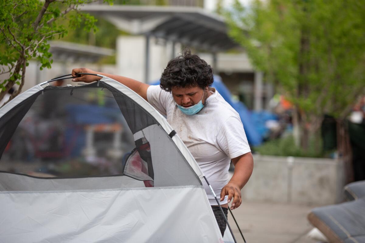 An unhoused resident of Toriumi Plaza in Little Tokyo starts to pack up his belongs