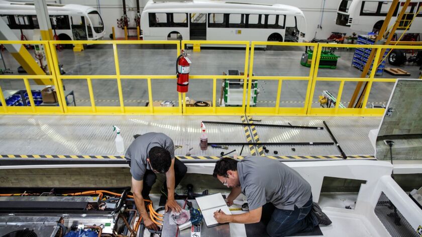 Workers assemble the air-conditioning unit for an electric bus made by Proterra at a factory in Los Angeles.